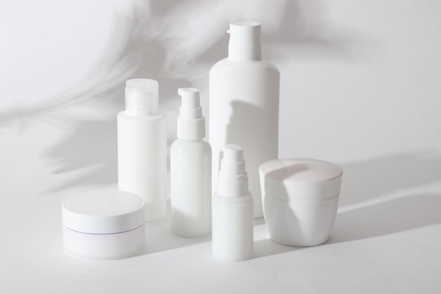 Set witte cosmetische flessen en potten met harde schaduwen. Thuis- en schoonheidssalon zorgconcept