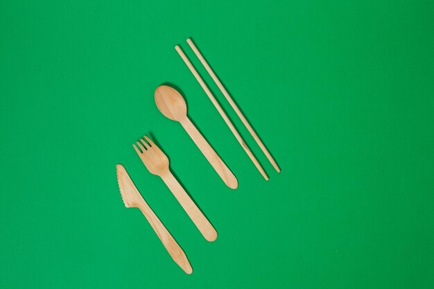 Set of wooden fork spoon knife bamboo toothbrush isolated on green background