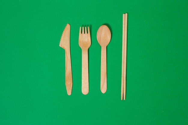 Set of wooden fork spoon knife bamboo toothbrush isolated on green background