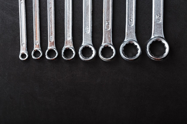 A set of wrenches in a row on a black background in a row. Top view, free space