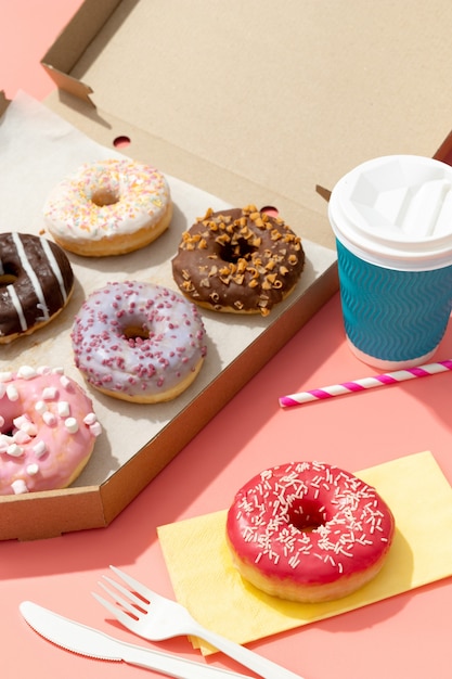 set of yummy colorful donuts in paper box on pink surface