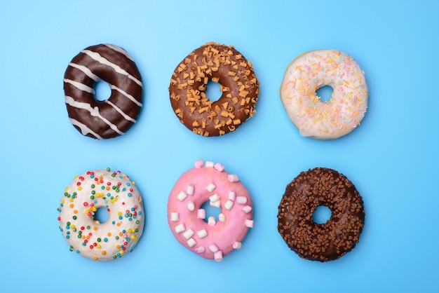 Set of yummy colorful pastel retro summer fashion donuts. Top above overhead flat-lay photo of six beautiful sugary objects isolated over blue surface