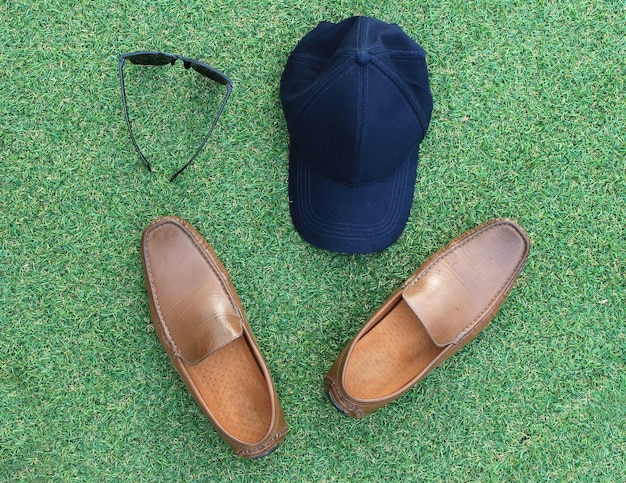 Sets of hat,sunglasses and shoes on green grass