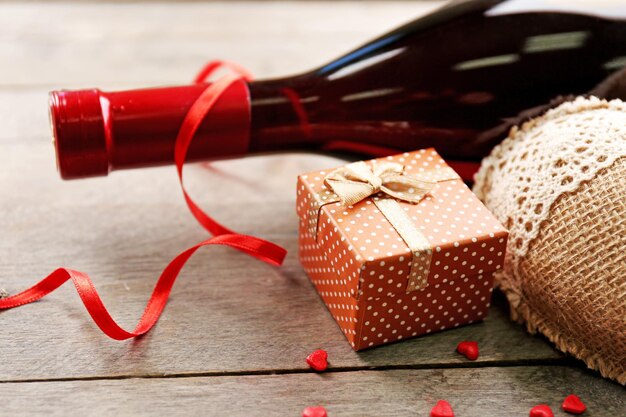 Impostazione di una bottiglia di vino, un regalo nella scatola e altre decorazioni, su fondo di legno