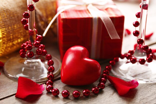 Setting of a bottle of wine, a gift in the box and other decoration, on wooden background