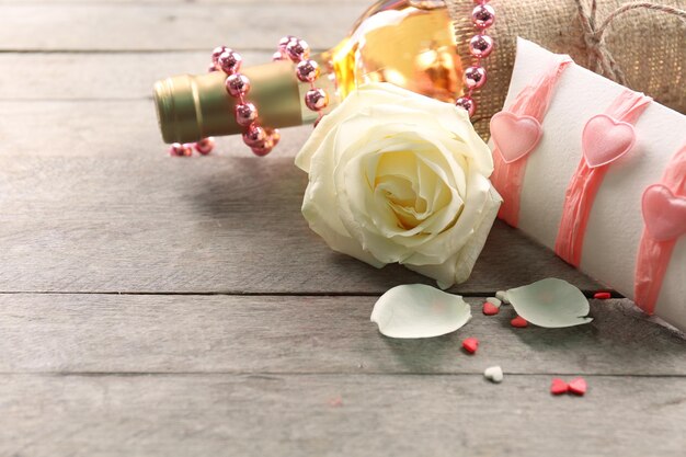 Setting of a bottle of wine, a gift in the box and other decoration, on wooden background