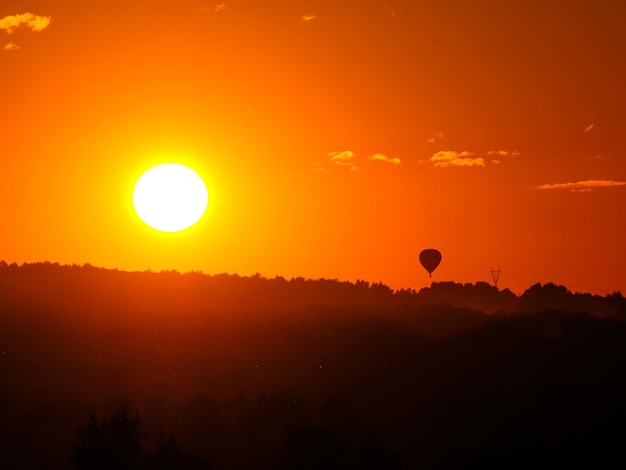 The setting sun and the silhouette of a hot air balloon in the
sky at sunset