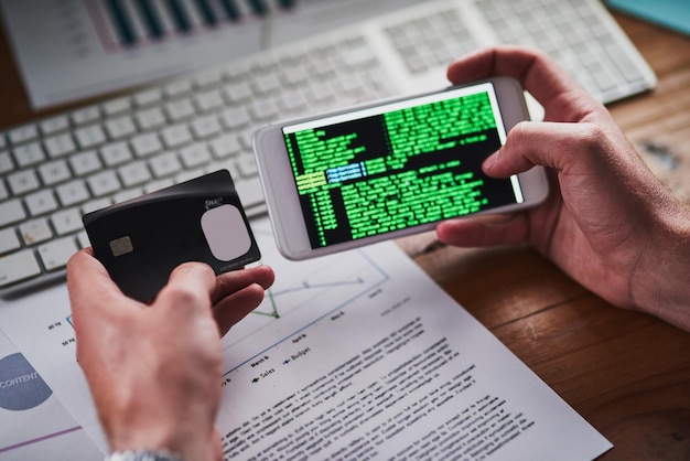 Setting up state of the art security features Shot of an unidentifiable programmer holding his credit card while programming on his smartphone