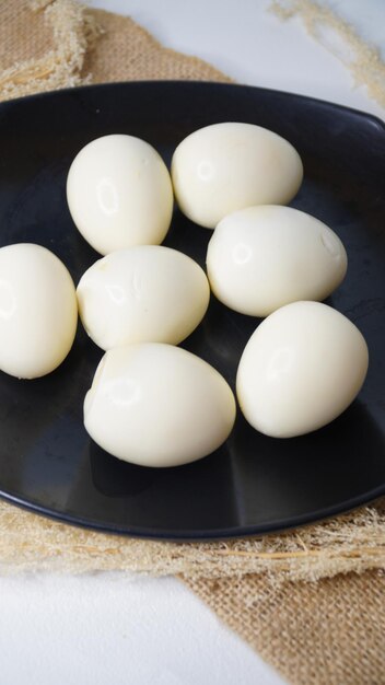 seven boiled chicken eggs on a black plate on a white background