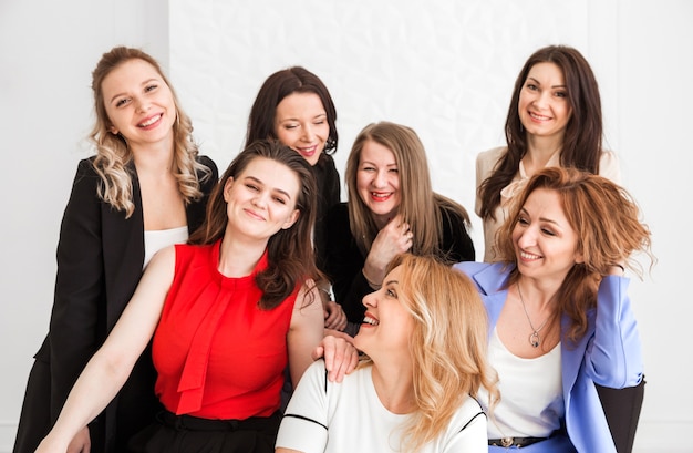 Seven diverse colleagues, co-workers stand ans seat together in office, hug each other.