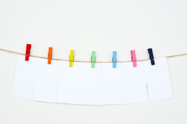 Photo seven empty white cards hang on colour clothespins, space for text, tag, word seven-letters, mock-up