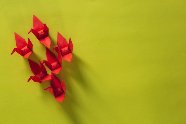 Семь красных птиц оригами летят во главе с розовой птицей, изолированной на белом, красный бумажный журавль оригами