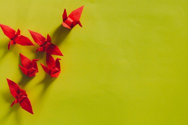 Seven red origami birds are flying leading by a pink bird\
isolated on whitered origami paper crane