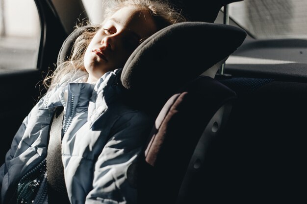 Photo seven-year charming girl sleeping in a children's car seat.