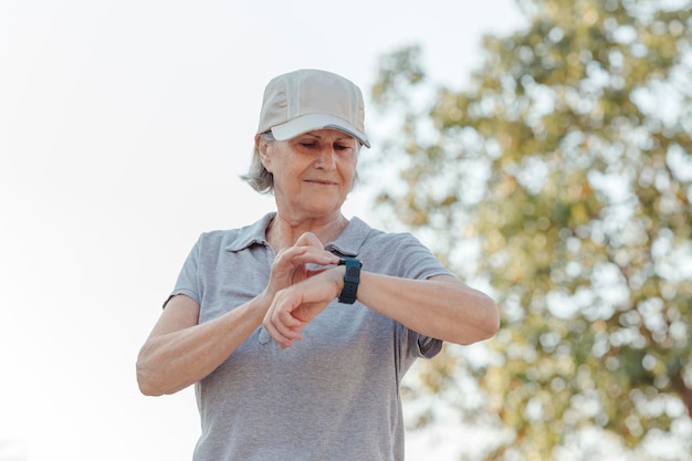 Seventyyearold woman looks at her outdoor sports watch