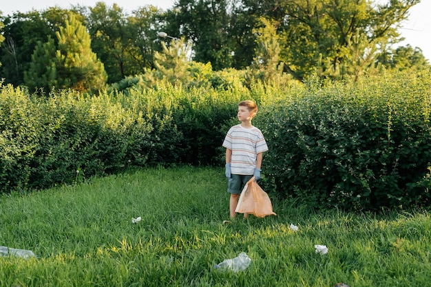 A sevenyearold boy at sunset is engaged in garbage collection in the park Environmental care recycling