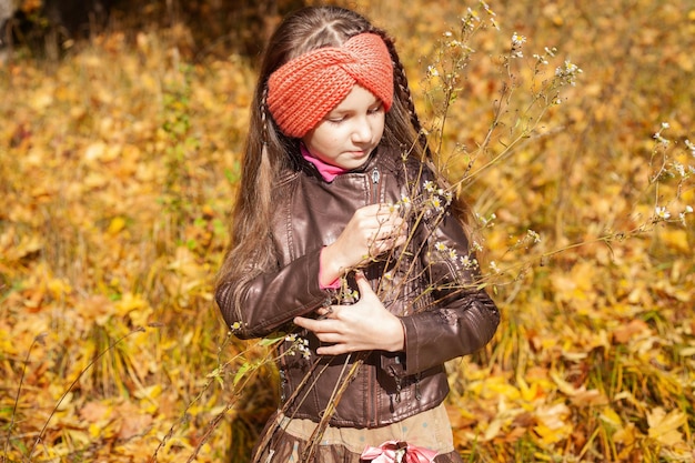 秋の黄葉を背景に革のジャケットを着た 7 歳の少女