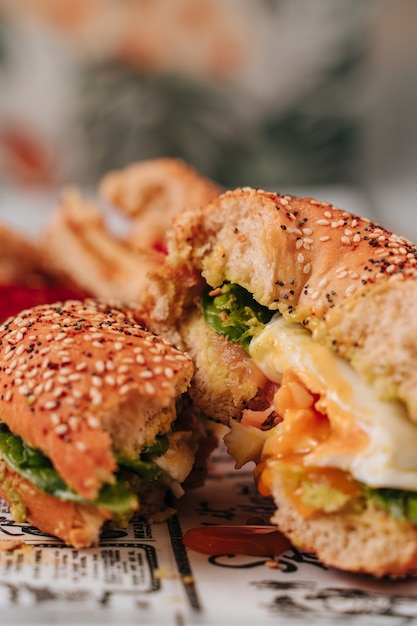 Several bagels cut in half with sesame and chia bread, inside it contains various ingredients such as tomato, ham, avocado, fresh cheese, chicken in strips.