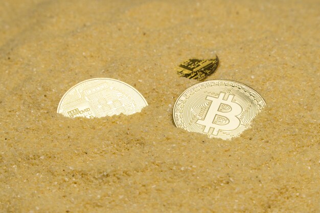 Several bitcoin crypto coins on brilliant golden sand. finding and mining cryptocurrency