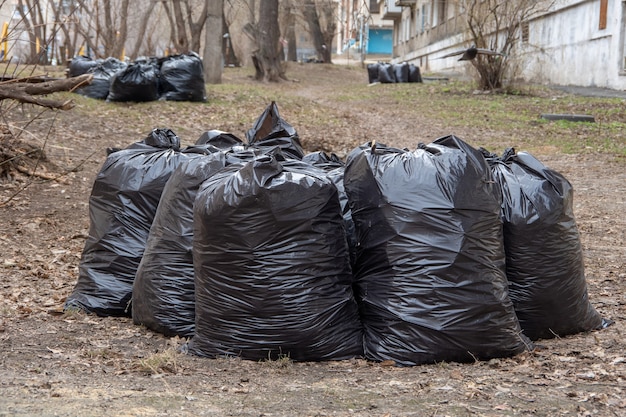 Несколько черных мешков для мусора на земле для передачи в службу вывоза мусора.
