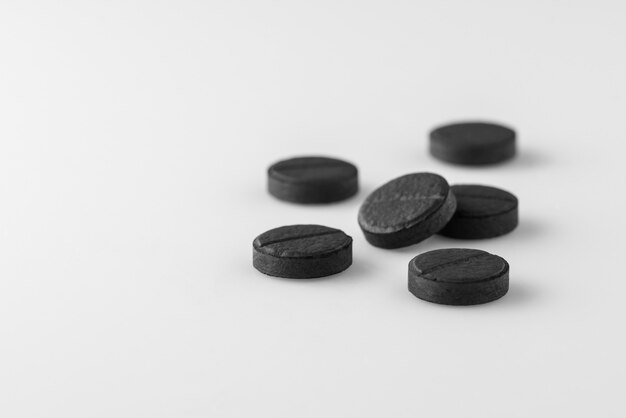 Several black medical activated charcoal pills on white background. Isolated