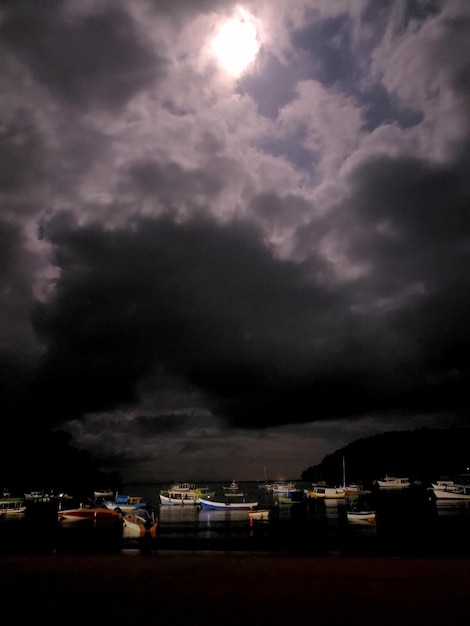 Several boats on the beach at night with the light present