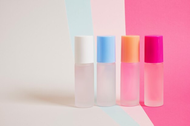 Several bottles of perfume of different colors on a bright multicolored background, mock up perfume bottles on a striped background, copy space, cosmetics background