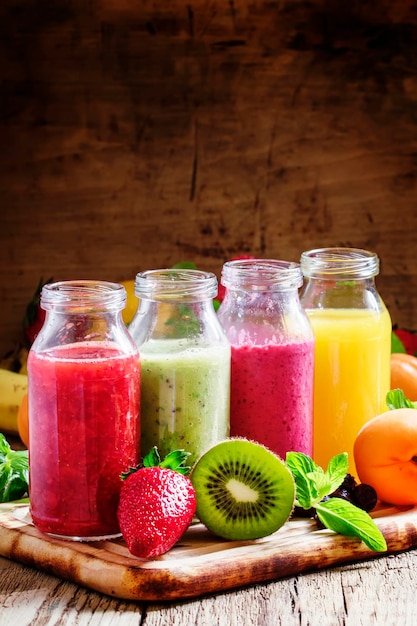 Photo several bottles with fruit and berry juices vintage wooden background selective focus