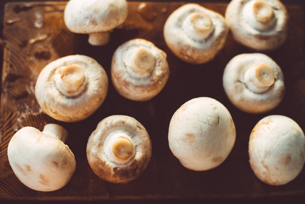 Several champignons on a wooden cutting board 