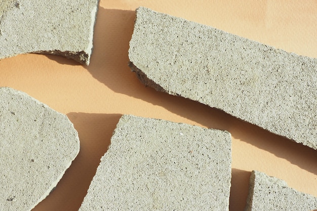 Several concrete chips on a beige paper background in harsh light with shadows. flat layout, top view.