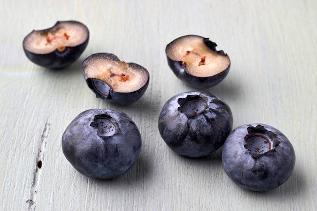 Several cut blueberries on a wooden blue background