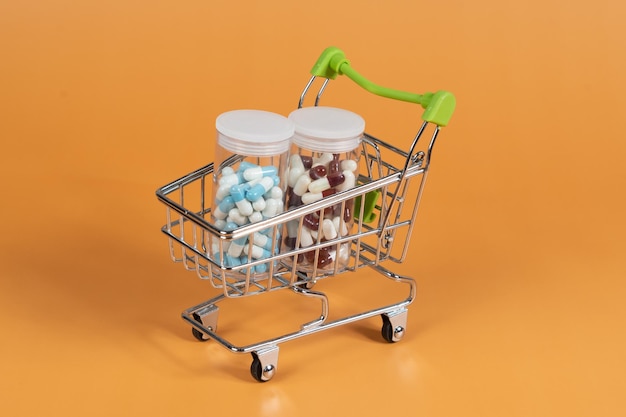 Several different packages of pills in small shopping car on green background medicine order delivery concept