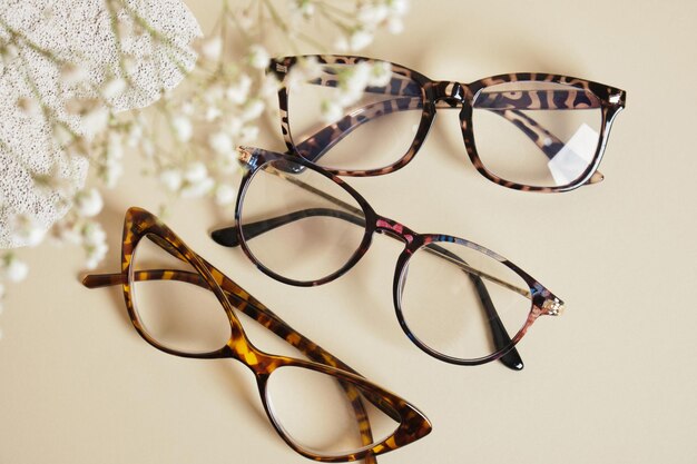 Several different trebdy eye glasses with fashion frames and concrete podium on beige background