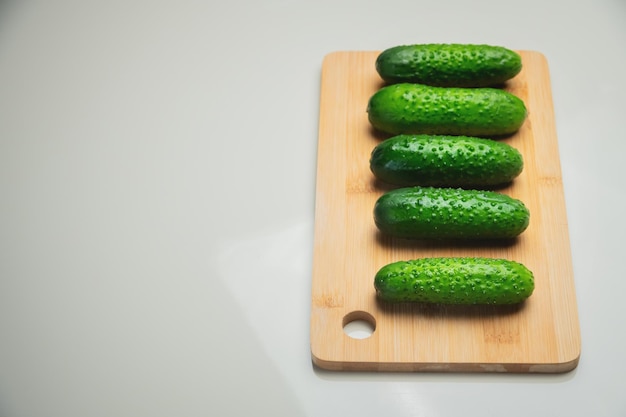 Photo several fresh green cucumbers on a wooden cutting board