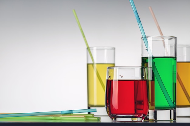 Several glasses of different multicolored soft drinks