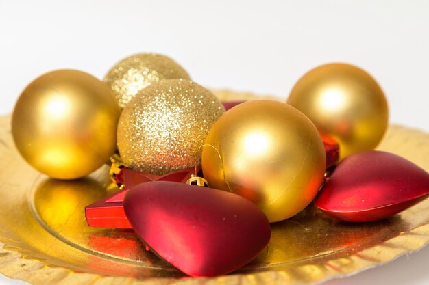 Several golden Christmas balls stars and red hearts on a plate of party