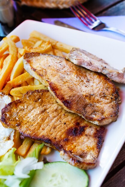 Several Grilled steak, French fries and vegetables