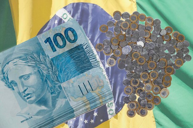 Foto diverse centinaia di banconote e monete di reais dal brasile su sfondo a colori brasiliani