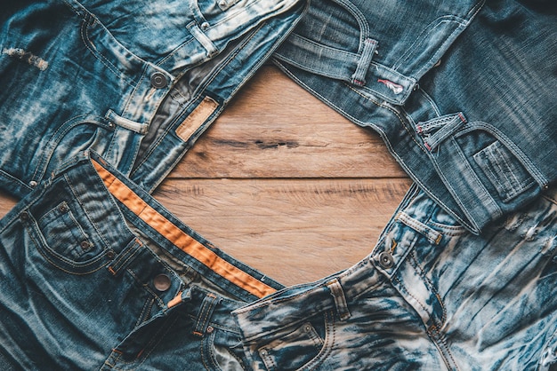 Foto diversi jeans sono posizionati sul pavimento di legno.
