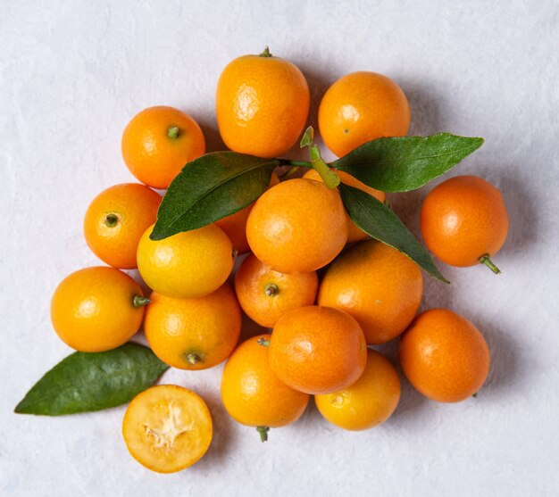 Several juicy fresh sweet kumquats on a white wooden table