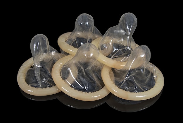 Several latex condoms on a dark mirror surface Means of contraception and protection