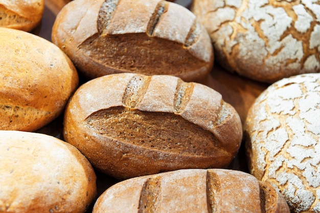 Several loaves of bread lie on a wooden tray