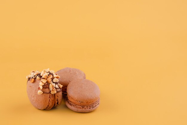 Several macaroons of various flavours on yellow background Space for text