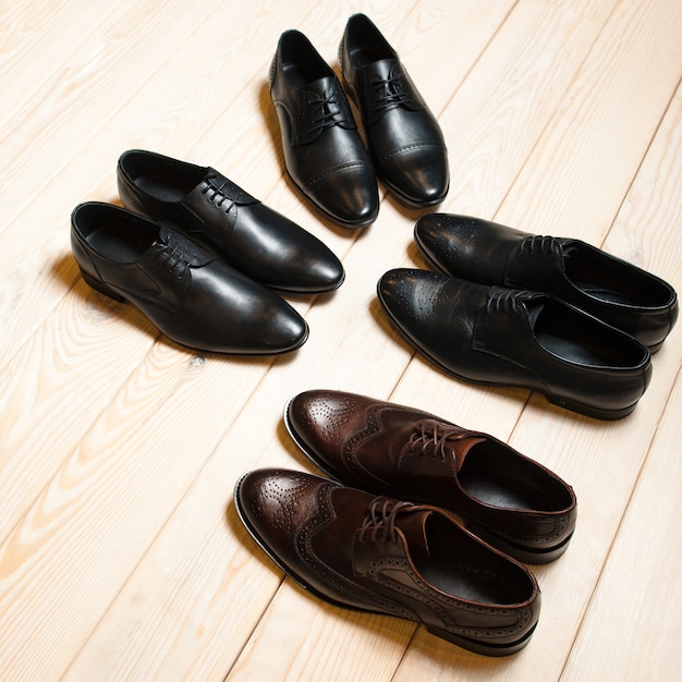 Several male classic shoes on wooden floor.