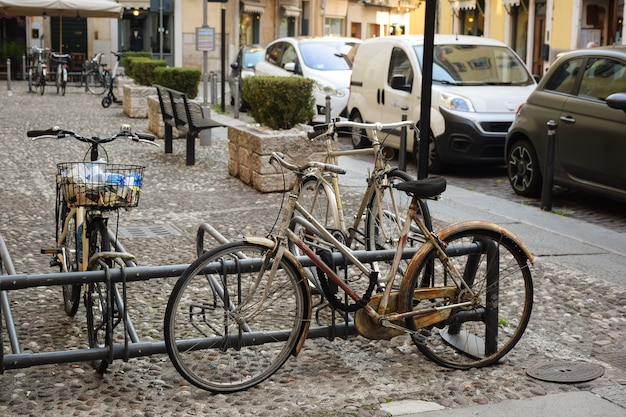 Several old bicycles stand on the cobblestones of the old city, strapped to the fence