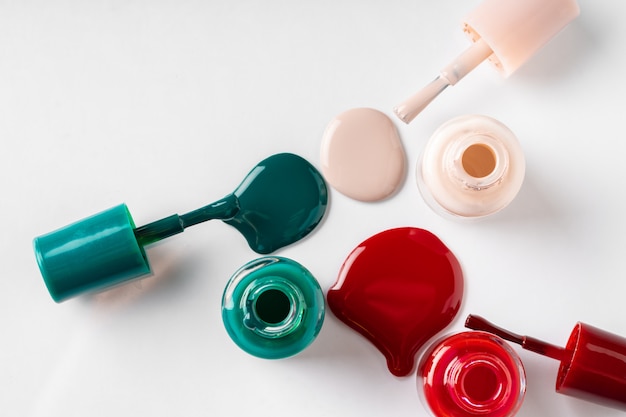 Several opened bottles of nail polish on white background