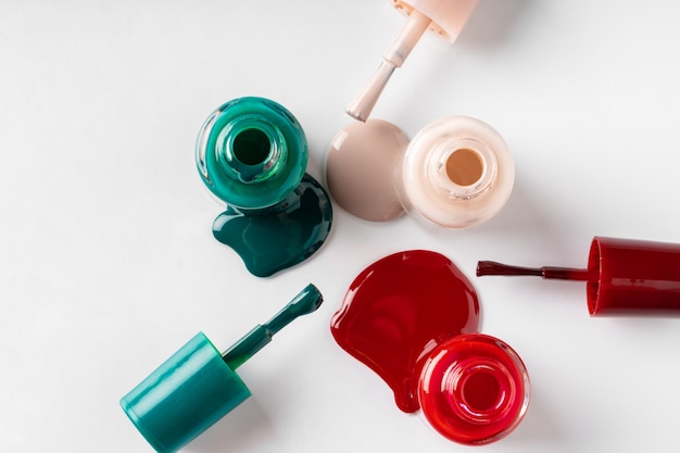 Several opened bottles of nail polish on white background