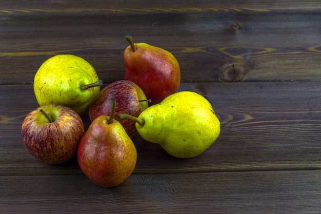 Several pears and apples on a wooden table