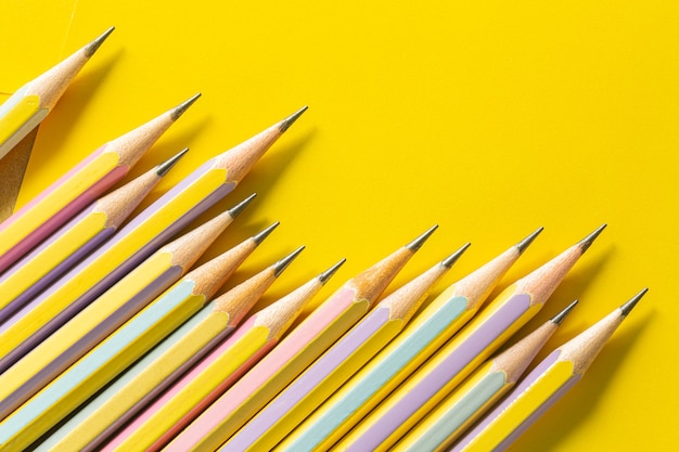 노란색 종이에 여러 연필노란색 뒷면에 격리된 여러 색 연필의 학교 테두리로 돌아가기