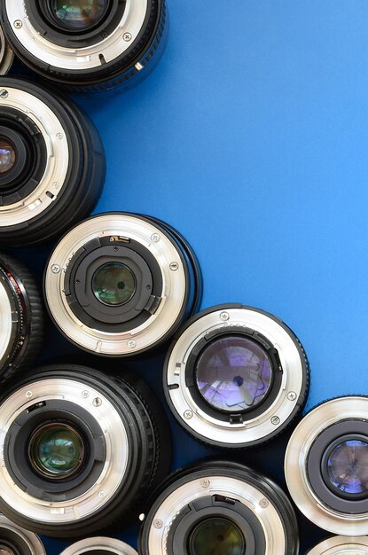 Several photographic lenses lie on a bright blue background. Space for text